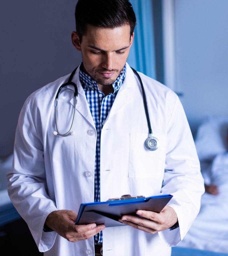 Smiling doctor writing on clipboard in ward